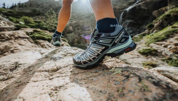 Salomon-Schuhe auf den Füßen eines Wanderers. Hochwertige Ausrüstung für aktive Abenteuer. Jetzt mehr erfahren!