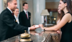 Out-of-focus image of a guest and hotel receptionists at check-in