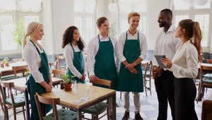 Restaurant staff standing around in a team meeting with their manager