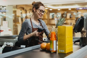 Female supermarket worker smiling and scanning items at checkout