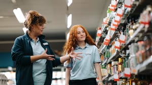 Weibliche Supermarktmanagerin und Angestellte betrachten Produkte im Regal. Effektive Mitarbeiterbindung für reduzierte hohe Mitarbeiterfluktuation.